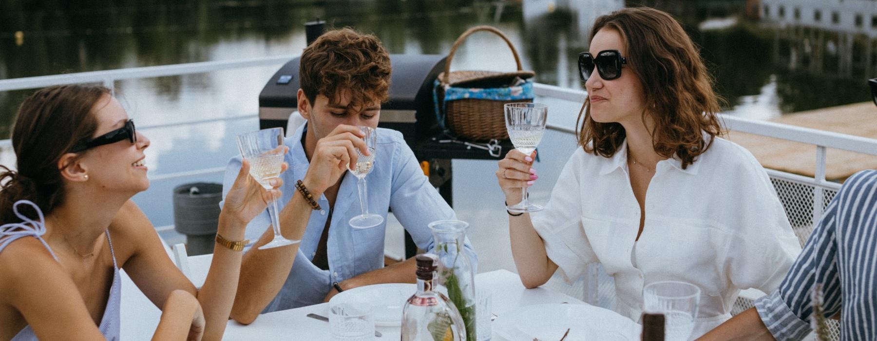 a group of people sitting at a table with food and drinks